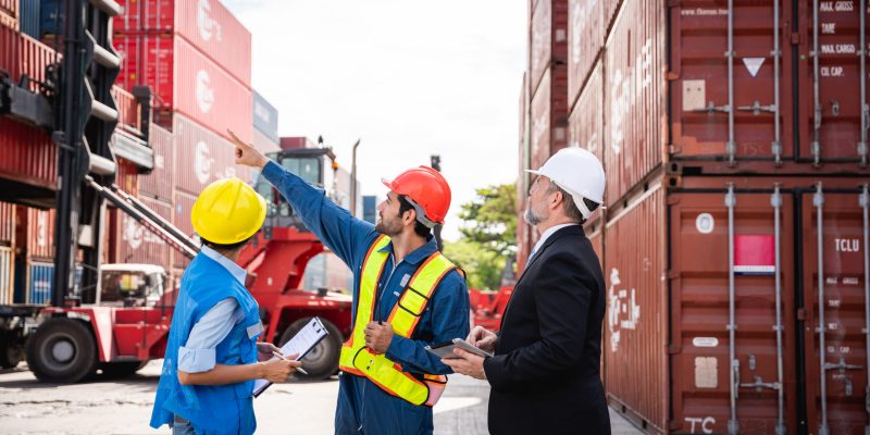 Businessman,  Engineer or foreman talking and checking inventory or task details at container yard warehouse., Logistics concept inside the shipping, import, and export industries.